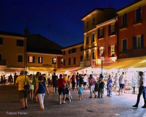 uma multidão de pessoas andando em torno de uma rua à noite em Suite In Centro Storico em Caorle