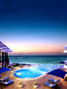 a swimming pool with chairs and umbrellas and the ocean at Private Room In Apartment with Sea & Hilton View in Alexandria
