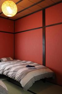 a bed in a room with a red wall at 小さなお宿 乃むら in Kanazawa