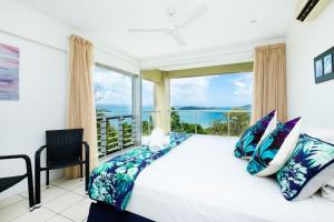 a bedroom with a bed and a large window at Ocean Sunsets - Skiathos in Hamilton Island