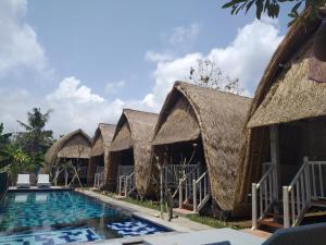 a row of huts with a swimming pool at HoneyBee Huts in Nusa Lembongan