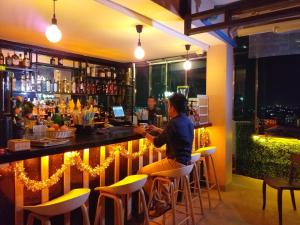 a woman sitting at a bar in a restaurant at Hotel Broadway Yangon in Yangon
