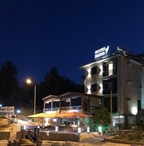 a building with a sign on top of it at night at Hotel Hugo in Altınoluk