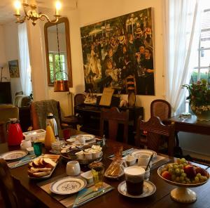 a dining room table with food and a painting on the wall at Les rêves d'Angèle in Crain