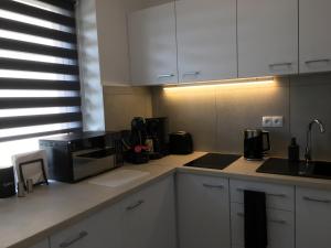 uma cozinha com armários brancos e um micro-ondas preto em Studio Fibra Lungo em Rybnik