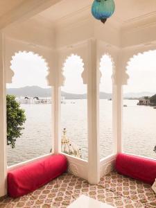 
a red and white bed sitting next to a lake at Jagat Niwas Palace in Udaipur
