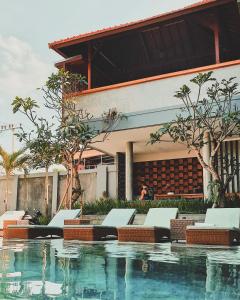 a swimming pool with chairs and a building at Perissos Echo Beach in Canggu