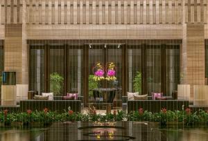 a lobby of a building with tables and flowers at CITIC Pacific Zhujiajiao Jin Jiang Hotel in Qingpu