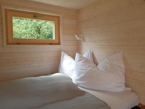 una camera da letto con un letto con cuscini e una finestra di Tiny House Steirermadl a Birkfeld