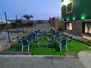 un groupe de chaises et de tables sur une pelouse verte dans l'établissement Hostal Catedritos Ibéricos A-5 Km 154 A 5 KM DE OROPESA A 1 KM DE HERRERUELA DE OROPESA, à Herreruela de Oropesa