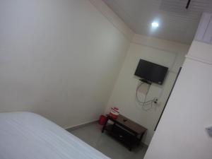 a bedroom with a bed and a tv on the wall at Rose Cottage in Mount Ābu