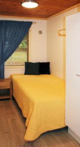 a bedroom with a yellow bed with a window at Tervakosken Tervaniemi hirsimökki & oma sauna in Tervakoski