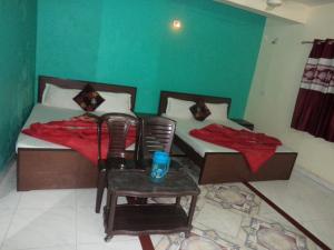 2 camas en una habitación con mesa y 2 sillas en Shri Shanti Villa en Mount Ābu
