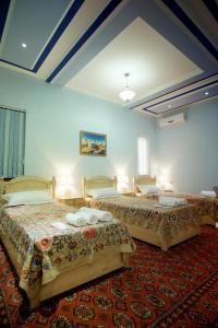 two beds in a room with blue walls at Ismail in Bukhara
