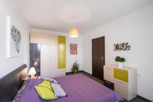 een slaapkamer met een paars bed met gele kussens bij NC Apartment Ruse in Ruse