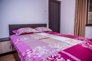 un letto rosa con trapunta e cuscini rosa e bianchi di EUROPE GUEST HOUSE § КЪЩА ЗА ГОСТИ ЕВРОПА a Veliko Tŭrnovo