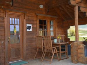 a porch of a wooden cabin with a table and chairs at Ferienhof Pfeiffer in Buchen