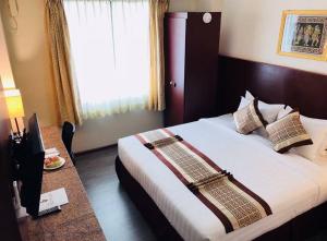a hotel room with a bed and a window at Hotel Broadway Yangon in Yangon