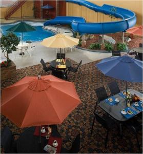 a patio with tables and umbrellas in front of a pool at Grand Gateway Hotel in Rapid City