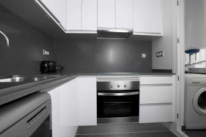 cocina en blanco y negro con fogones y fregadero en Apartamentos Sunway Talaia, en Sitges