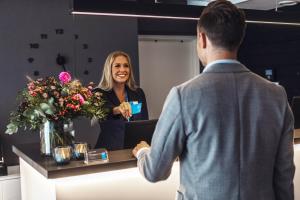 a woman standing at a counter with a man at Sky Hotel City Apartments in Linköping