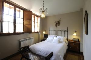 una camera da letto con un letto, una sedia e finestre di Apartamentos Casa María Juanín a Collanzo