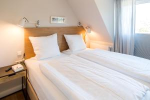 a large white bed in a room with a window at Welle 11 Sylt in Westerland (Sylt)