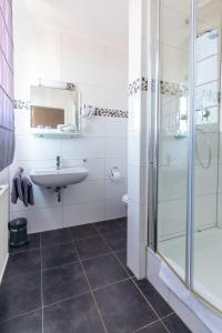a white bathroom with a sink and a shower at Hotel Garni Zum Dorfbrunnen in Bornheim