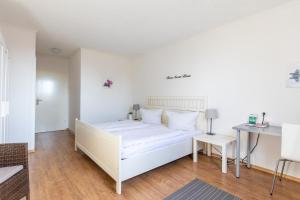 a white bedroom with a white bed and a table at Hotel Garni Zum Dorfbrunnen in Bornheim