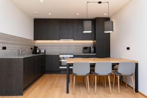 a kitchen with black cabinets and a wooden table and chairs at Self-check-in 2 bedroom apartment with a terrace and free parking in Tallinn