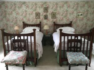 a bedroom with two twin beds and two chairs at O'Harabrook Country House in Ballymoney