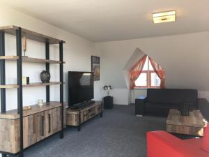 a living room with a couch and a tv at Penthouse Belle Vue in Bergen aan Zee