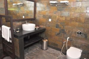 a bathroom with a sink and a toilet and a mirror at Canaan Beach Resort in Nīleshwar +29 photos