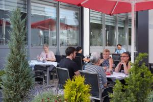 a group of people sitting at tables in a restaurant at Hotel Stadt Tuttlingen in Tuttlingen
