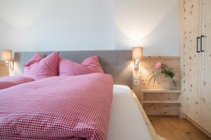 a bedroom with a bed with a pink comforter at Tschott Hof in Villandro