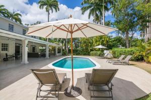 an umbrella and chairs next to a swimming pool at Royal Palms, St James in Saint James