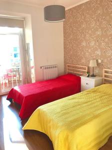 een slaapkamer met 2 bedden met rode en gele lakens bij Luxury part of the city - Modern Apartment with Airconditioning - near Subway in Lissabon