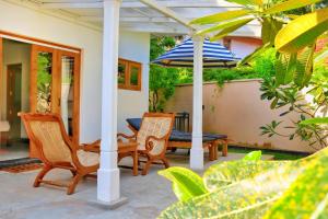 eine Terrasse mit Stühlen, einem Tisch und einem Sonnenschirm in der Unterkunft BoBo's Bed & Breakfast in Ahungalla