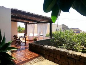 een patio met een stenen muur en een tafel en stoelen bij Dammuso Surya Cloe in Pantelleria