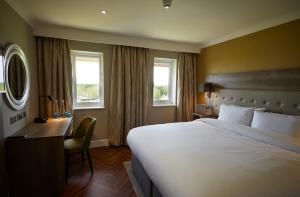 a hotel room with a bed and a desk and windows at Wychwood Park Hotel and Golf Club in Crewe +55 photos