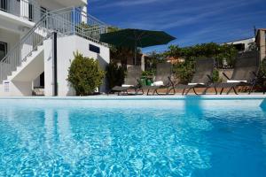 a swimming pool with chairs and an umbrella at TayLa-Apartment Vodice in Vodice