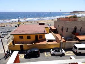 ein gelbes Gebäude mit Autos vor einem Strand in der Unterkunft Apartamentos Medano - Duplex Sea Views in El Médano
