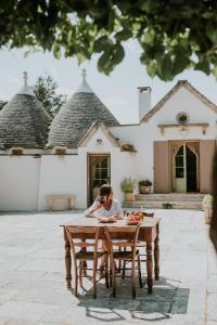 a woman sitting at a table in front of a house at Trulli d'Itria in Martina Franca