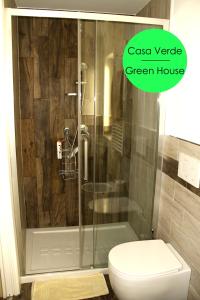 baño con ducha, aseo y una casa verde en Casa Vacanze Cozy House Matera en Matera
