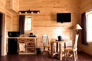 a kitchen with a table and chairs and a television at Cabins of Mackinac & Lodge in Mackinaw City