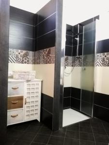 y baño con ducha y azulejos blancos y negros. en Dammuso Surya Oleandro en Pantelleria