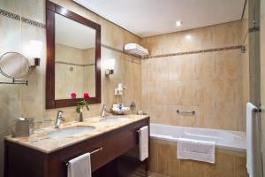 a bathroom with a sink and a tub and a mirror at Khalidiya Palace Rayhaan by Rotana, Abu Dhabi in Abu Dhabi