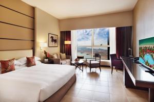 a hotel room with a large bed and a living room at Khalidiya Palace Rayhaan by Rotana, Abu Dhabi in Abu Dhabi