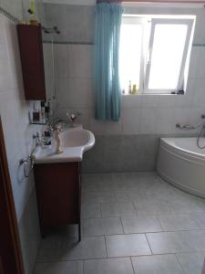 a bathroom with a sink and a tub and a window at Dora's Apartment 5 min from airport in Spata