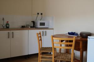 eine Küche mit einem Tisch, Stühlen und einer Mikrowelle in der Unterkunft Littlestone Hotel in New Romney